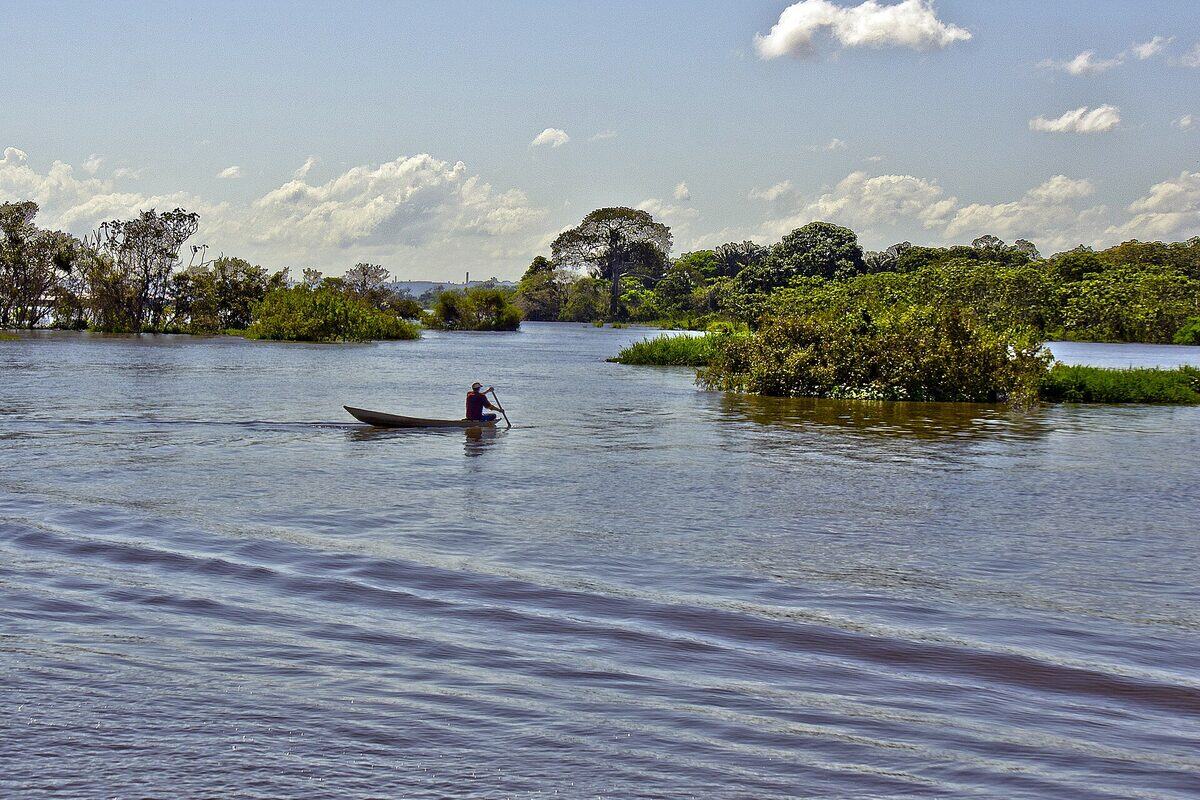 Canoa de madeira remando nas águas escuras do Rio Negro